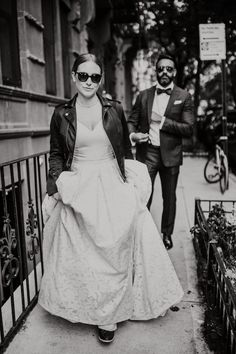 a man and woman walking down the street in black and white, dressed in vintage clothing