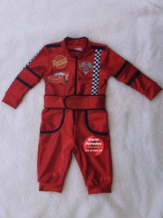 a child's red racing suit laying on top of a white blanket with checkered trim