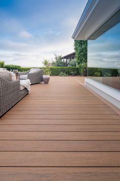 a wooden deck with pillows on it next to a window and bushes in the background