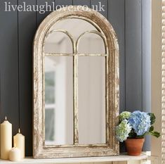 a mirror sitting on top of a shelf next to a vase with flowers in it