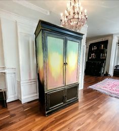 a large armoire in the middle of a room with wood floors and chandelier