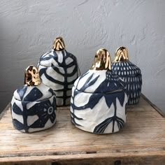 three blue and white ceramic containers sitting on top of a wooden table