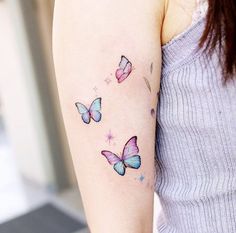 a woman's arm with three colorful butterflies on the left side of her arm