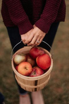 a woman holding a basket full of apples