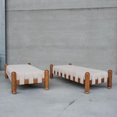 two wooden benches sitting next to each other in front of a cement wall and concrete floor