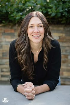 a woman sitting at a table smiling for the camera