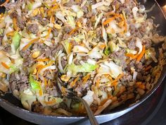 a skillet filled with meat and vegetables on top of a stove burner next to a spatula