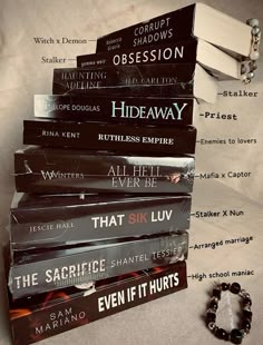 a stack of books sitting on top of a bed next to a bracelet and necklace