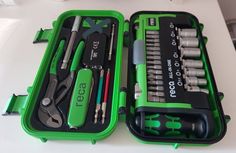 an open green tool box filled with tools on top of a white counter next to scissors and pliers