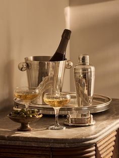 an assortment of wine glasses and bottles on a marble top table with a silver tray