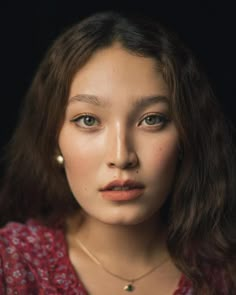 a close up of a person wearing a red shirt and gold necklace with an earring