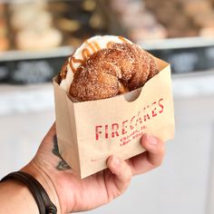 a hand holding a paper bag filled with doughnuts