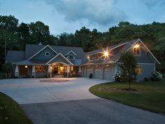 a large house lit up at night with lights on it's windows and driveway