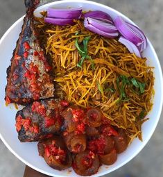 a white plate topped with meat and veggies next to red onion wedges