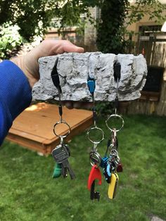 a person holding keys in front of a stone block with several key chains hanging from it