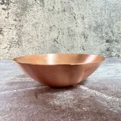 a large metal bowl sitting on top of a gray countertop next to a wall