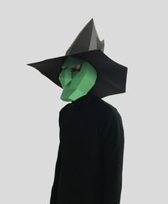 a person wearing a paper hat and black coat with a green mask on their head