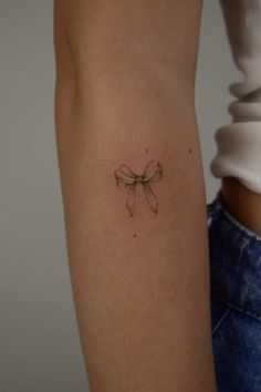 a woman's arm with a small bow tattoo on it