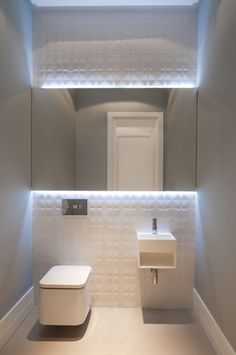 a white toilet sitting under a bathroom mirror next to a sink in a room with grey walls