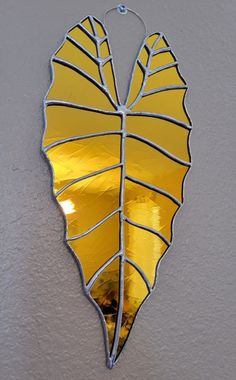 a yellow leaf shaped mirror hanging on the wall