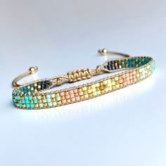 a bracelet with multicolored beads and gold clasps on a white table top