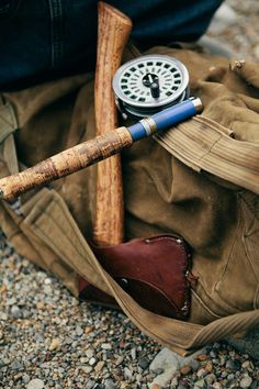 a fishing rod and reel in a duffel bag on the ground next to a man's boots