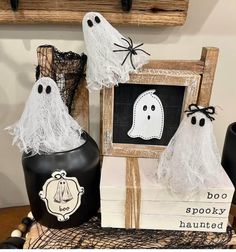 three halloween decorations are sitting on a table next to a chalkboard with ghost faces