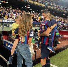 a woman holding a child in her arms at a soccer game