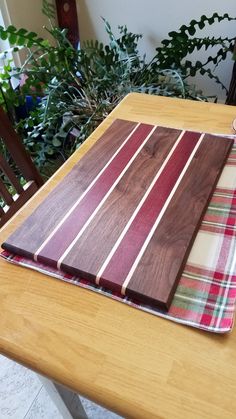 a wooden cutting board sitting on top of a table next to a potted plant