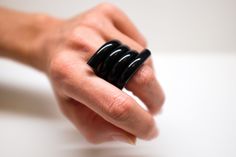 a person's hand holding a black ring