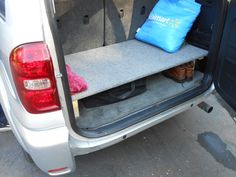 the back end of a white van with a blue bag and some shoes in it