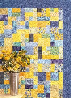 a vase filled with yellow flowers sitting on top of a table next to a blue wall