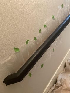 an arrow is taped to the wall by plastic wrap and green leaves are scattered around it