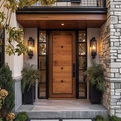 a wooden door with two planters in front of it on the side of a house