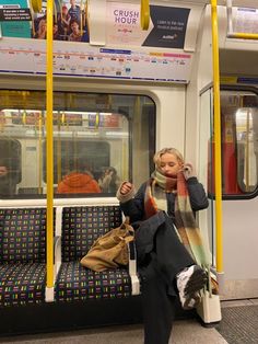 a woman sitting on a subway train with her hand up to her face and looking out the window