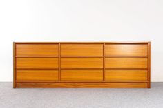 a large wooden dresser sitting on top of a floor next to a white wall in an empty room