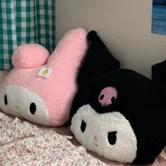 two hello kitty stuffed animals laying on top of a bed next to each other,