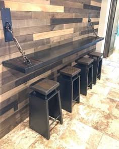 a row of stools in front of a wall with wooden planks on it