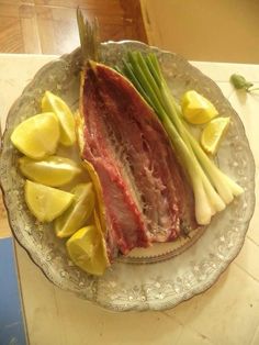 a plate topped with meat and vegetables on top of a table next to a knife