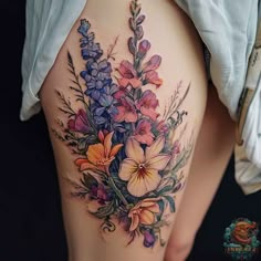 a woman's thigh with flowers and leaves on the side, in front of her