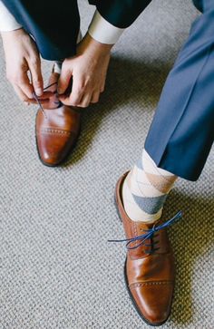 a man tying his shoelaces while sitting on the floor