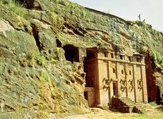 an ancient building with steps leading up to it on the side of a cliff face