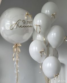 white balloons with gold ribbons and writing on them