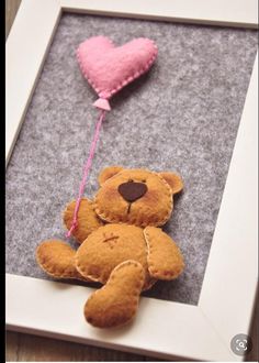 a teddy bear with a heart shaped balloon hanging from it's side in a frame