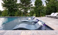 an outdoor swimming pool with lounge chairs and trees in the backgroung area