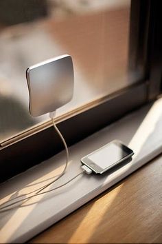 an electronic device is plugged into a charger on a window sill in the sunlight