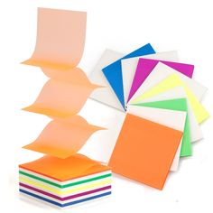 there are many different colors of paper on the white table and one is folded up