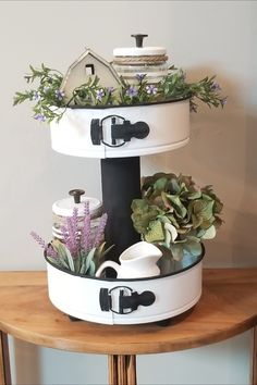 a round table topped with a white container filled with plants and other things on top of it