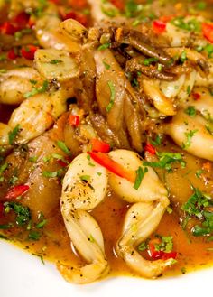 a white plate topped with pasta covered in sauce and garnished with parsley