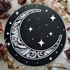 a black and white moon with stars in the sky surrounded by dried flowers on a table